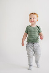 Adorable toddler boy playing and standing at home, having fun isolated on white background studio, copy space. Child play and smile. Little kid standing on floor in sunny room. Closeup. Place for text