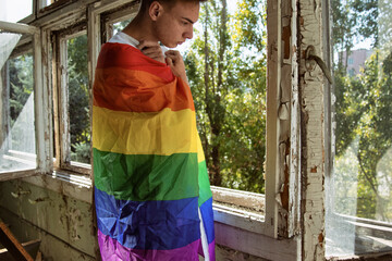 Sadness, pain and loneliness. Young attractive guy with a gay flag.	Sad man.
