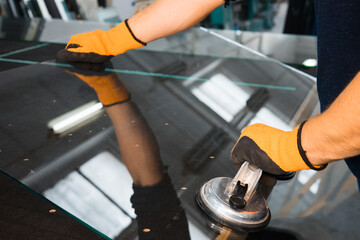 A glazier in a glass factory removes heavy glass using suction cups, specialized industrial tools