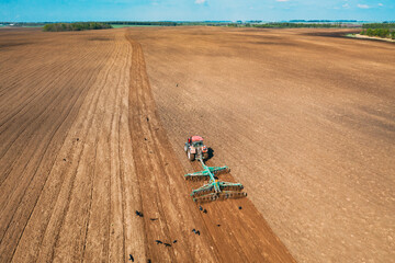 Aerial View. Tractor Plowing Field In Spring Season. Beginning Of Agricultural Spring Season. Cultivator Pulled By A Tractor In Countryside Rural Field Landscape.