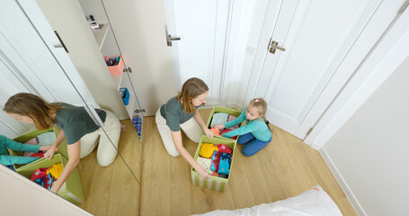 Mom and daughter sort clothes, put things in the closet