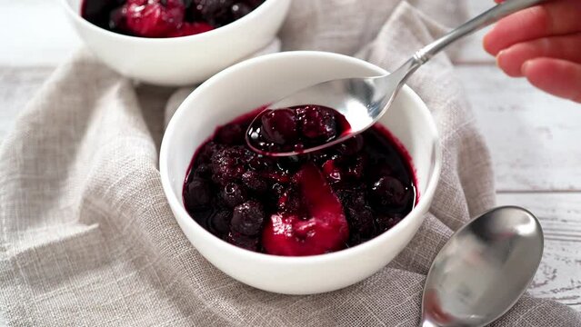 Homemade mix berry compote in small white bowls on a wooden table.