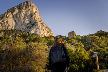 Adventure Concept with Hiker Girl Back View Climbing the Peñon de Ifach Mountain in Calpe Town Carrying Backpack