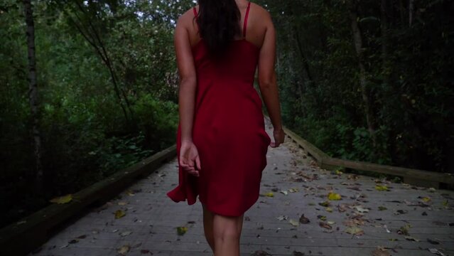 Sexy woman in red dress pinup in a park at sunset. Slow motion.