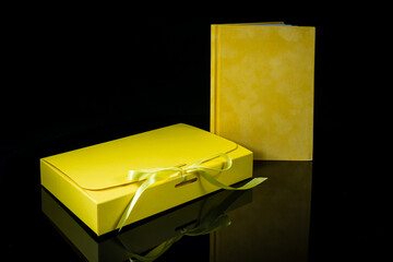 Best gift for men. Man gift concept. Yellow notebook with yellow gift box on black background. Copy space. Valentine's day, wedding, birthday and special occasion gift concept. Copy space for text.