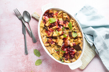 Flat lay. Serving freshly baked bread pudding with raising and almond slivers in a white casserole...