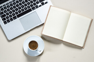 bright feminine banner or header with a coffee, stylish workspace with laptop computer, modern office accessories and a small notebook on a blush table, top view, flat lay