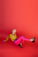 full length of albino woman in heeled sandals and trendy outfit posing on carmine pink.