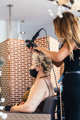 Hairdresser drying the hair of a customer giving a perm