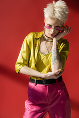 sunlight on face of albino woman with tattoo posing in stylish sunglasses on carmine pink.