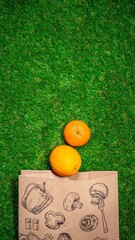 Naklejka premium Banana, red apple and different fruits with craft paper bag laying on grass, flat lay. Space for text. Zero waste concept.