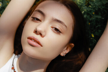 Fototapeta premium Top view of young woman looking at camera while lying on meadow.
