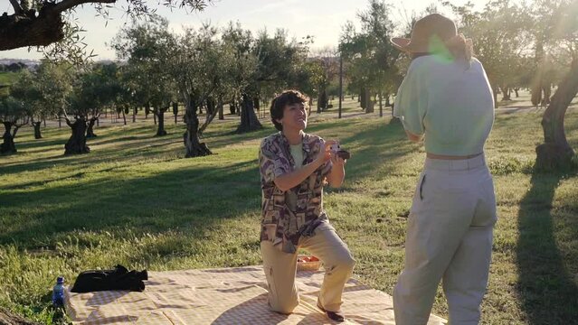 Wide shot slow motion homosexual marriage proposal gay lgbt exciting on a picnic in the park with sunset sunlight