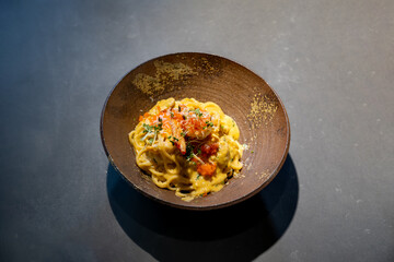 Spaghetti Carbonara pasta Egg and Cheese creamy cream sauce with Shrimp and micro herb decoration on the top of it of earthware circle bowl in studio light.