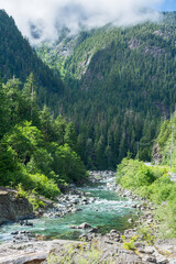 Obraz premium Mountain landscape with asphalt road and shallow river running through
