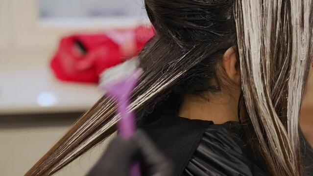 Hair highlighting procedure in a beauty salon - Closeup of woman head getting her hair coloured. High quality 4k footage