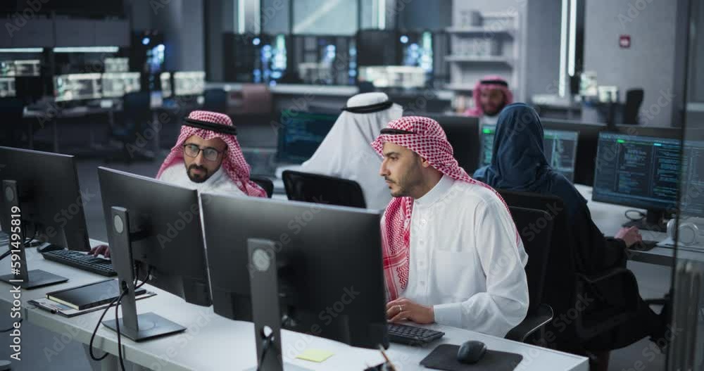 Fototapete Young Team of Arab Specialists Working on Computers and Having a Conversation at a Workplace. Two Male Software Developers Discussing a Solution for Their Generative Artificial Intelligence Project