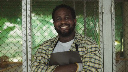 African farmer poses with crossed arms and a smile in a chicken farm