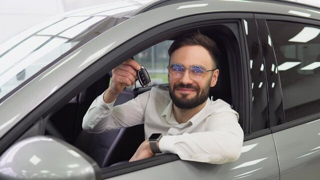 Business Man smiling and showing keys in a car dealership