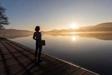 Freelancer standing with laptop looking at lake