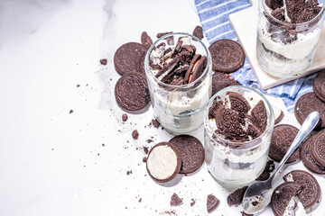 Cream and cookie layered dessert. Homemade oreo trifle, vanilla chocolate cookie layered cheese cake in glass, variation of traditional american breakfast dessert
