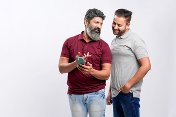 Two indian friend watching in smartphone and giving expression on white background.