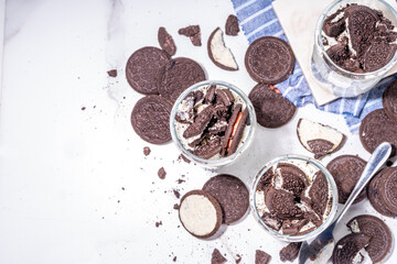 Cream and cookie layered dessert. Homemade oreo trifle, vanilla chocolate cookie layered cheese cake in glass, variation of traditional american breakfast dessert