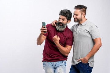 Two indian friend watching in smartphone and giving expression on white background.