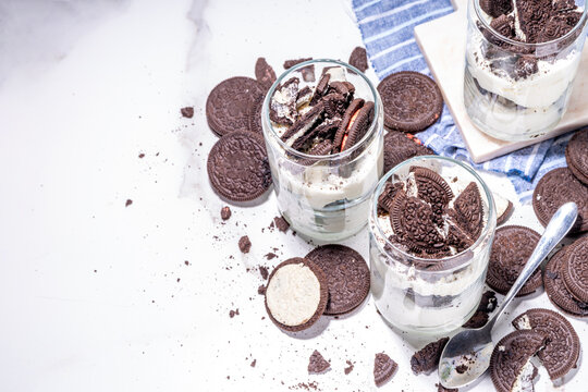 Cream and cookie layered dessert. Homemade oreo trifle, vanilla chocolate cookie layered cheese cake in glass, variation of traditional american breakfast dessert