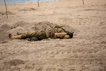 Foto op Plexiglas Historical reconstruction. Injured or dead World War II infantry  soldier  on the beach. View from the back.  Hel, Poland © krysek