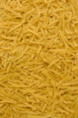 Yellow background with raw vermicelli noodles. Concept - pasta as background.