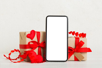 mobile phone with blank screen on colored background with hearts, calendar and gift box, valentine...