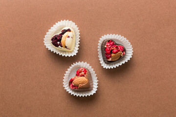 chocolate sweets in the form of a heart with fruits and nuts on a colored background. top view with space for text, holiday concept