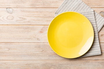 Top view on colored background empty round yellow plate on tablecloth for food. Empty dish on napkin with space for your design