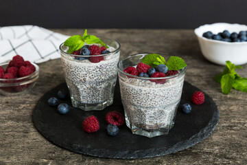Healthy breakfast or morning with chia seeds vanilla pudding raspberry and blueberry berries on table background, vegetarian food, diet and health concept. Chia pudding with raspberry and blueberry