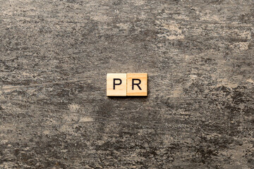 pr word written on wood block. public relation text on table, concept