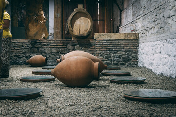 Clay pots for Georgian wine fermentation method in cellar in front of wine barrels