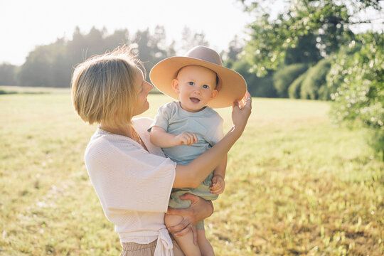 Happy mother with son wearing hat in nature on sunny day
