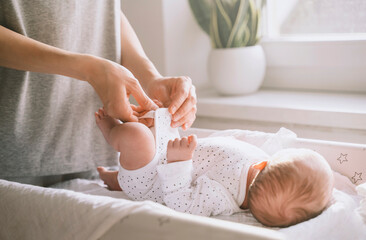 Mother changing clothes of baby at home