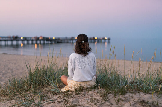 Frau am Strand bei Yoga am Strand mit Blick auf einen Steg in der Abendd&auml;mmerung
