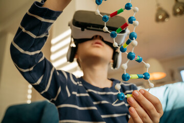 Boy examining DNA model through VR glasses at home
