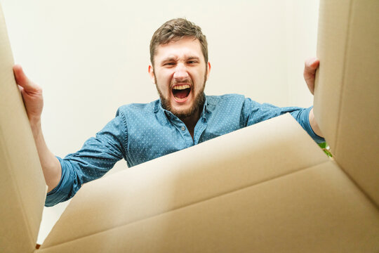 Young man screaming and looking inside cardboard box