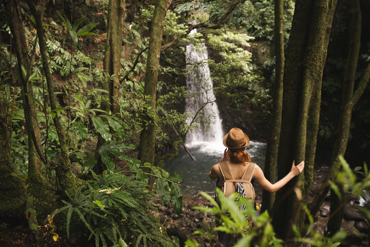 Woman wearing hat standing in front of waterfall