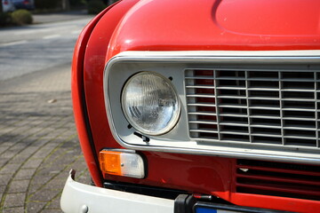 Scheinwerfer und Kühlergrill eines französischen Kleinwagen im Rot der Siebzigerjahre und...