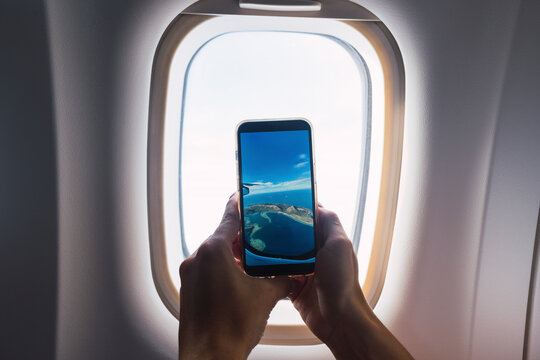 Man taking photo through airplane window