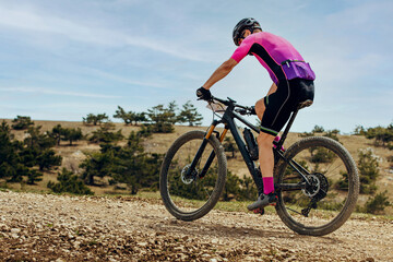 athlete mountainbiker biking uphill in cross-country cycling, outdoors summer race