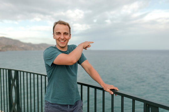 Happy man pointing towards sea
