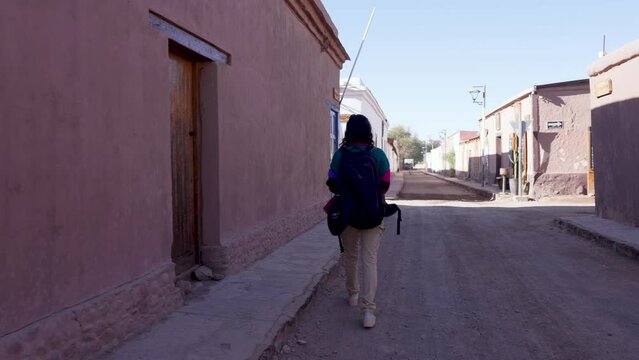 vista trasera mujer excursionista turista caminando con una mochila por las calles de San Pedro de Atacama