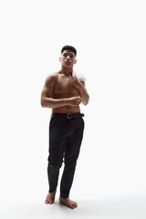 Fototapeta premium Full-length portrait of handsome young asian guy with muscular strong body posing shirtless in trousers over white studio background. Concept of fashion, style, body aesthetics, beauty, men's health