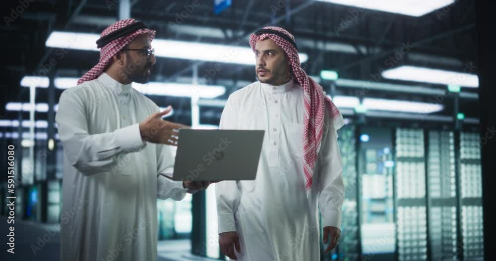 Aufkleber Middle Eastern Computer Engineer and Cybersecurity Specialist Work in Server Room, Talk, Perform System Maintenance Check with Laptop Computer. Specialists Doing Database Diagnostics in Data Center